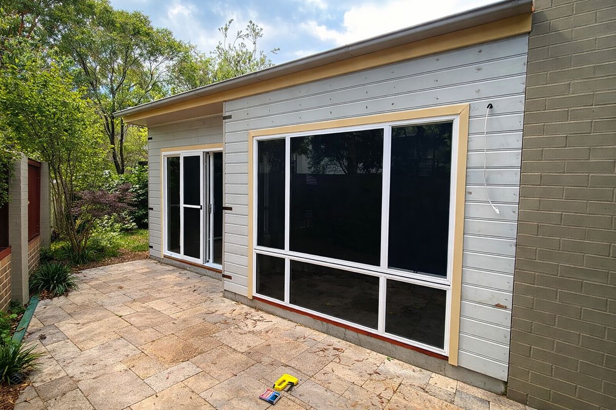 Single-storey home extension with new sliding doors, large windows, and paved outdoor area