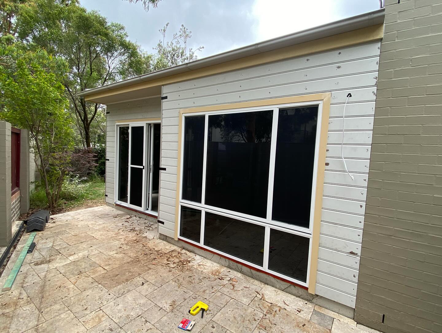 Rear home extension showcasing weatherboard cladding, aluminium windows, and seamless outdoor connection